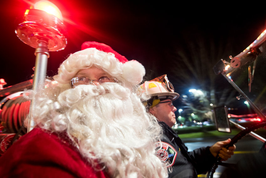 Riverside Fire Authority Assistant Chief Richard Mack drives Brian Thompson, dressed as Santa Claus, to the Borst Park Christmas Lights in an antique fire engine on Monday night.