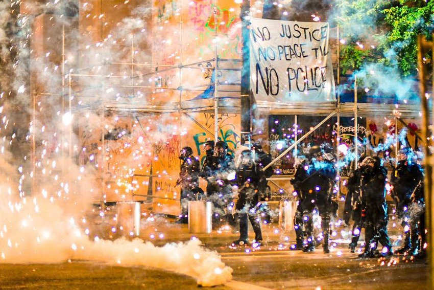 Tear gas is deployed as fireworks explode over law enforcement at the intersection of SW Main Street and SW 3rd Avenue in downtown Portland in early June.