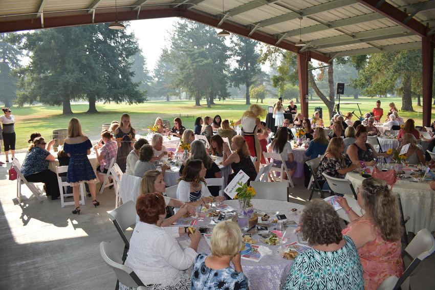 Attendees of an event gather at outdoor tables.
