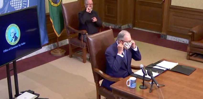 Gov. Jay Inslee removes a face mask moments before a press conference on Wednesday, April 29.
