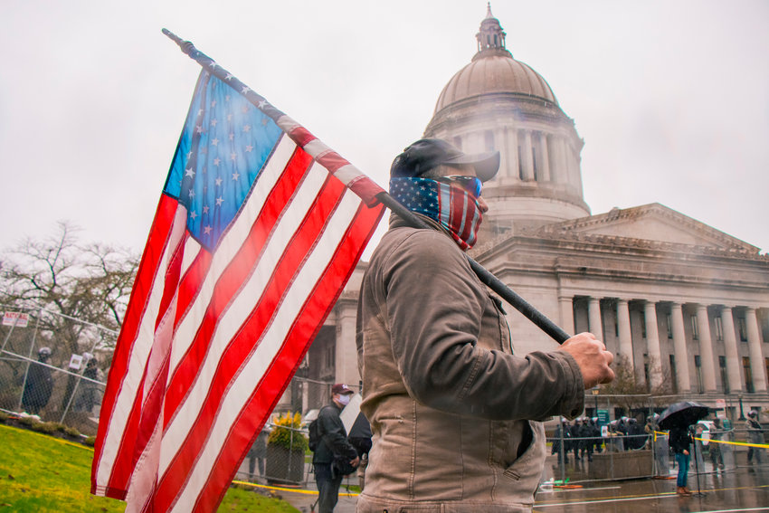 U.S. Army National Guardsmen and members of the Washington State Patrol stand within a fence as protests continue outside of the Washington State Capitol building on Monday in Olympia.
