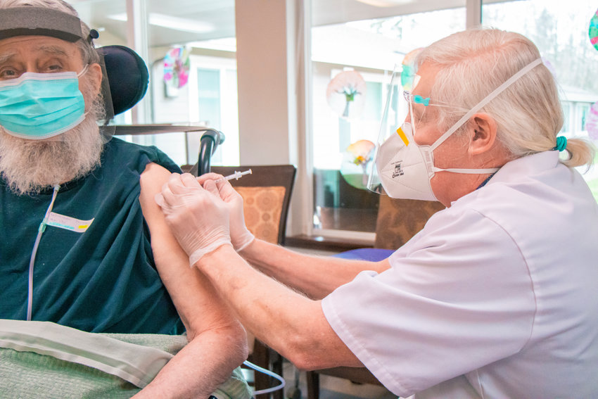 Will Dix, a Pharmacist with Walgreens for over 20 years, gives William Yeoman his first round of the Pfizer COVID-19 vaccine at Prestige Post-Acute and Rehab Center last January in Centralia.