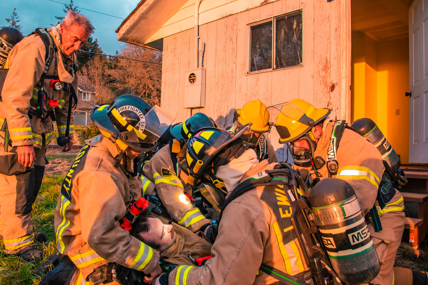 Lewis County Fire District 6 firefighters carry a colleague from the building they used for training on Monday.