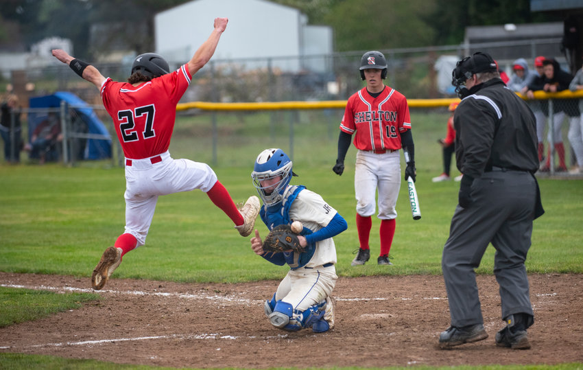 A Shelton player leaps into the air to avoid a tag by Rochester catcher Cody Morton in a 2A Evergreen Conference playoff opener Monday in Rochester.