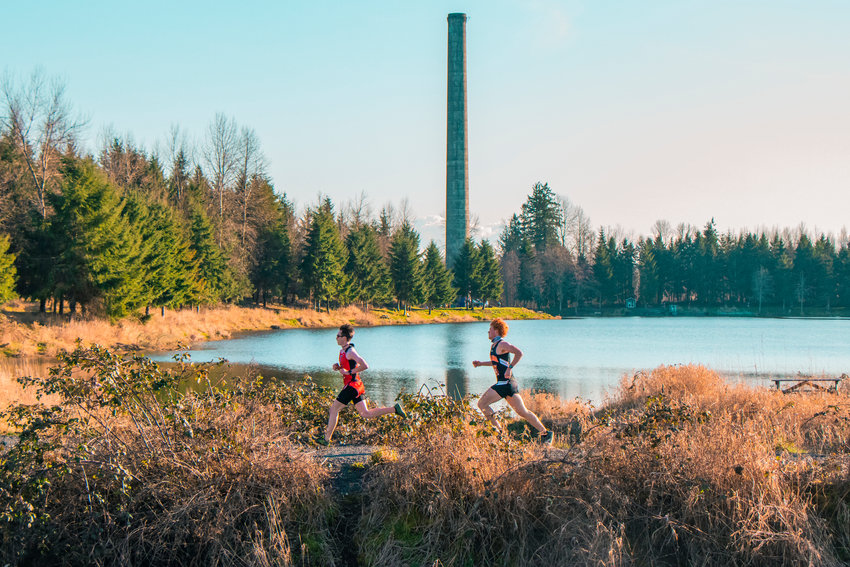 Toledo&rsquo;s Nicholas Marty leads Kalama&rsquo;s Addison Smee as the Carlisle Lake smokestack is seen in the background during a boys cross country meet in early March.