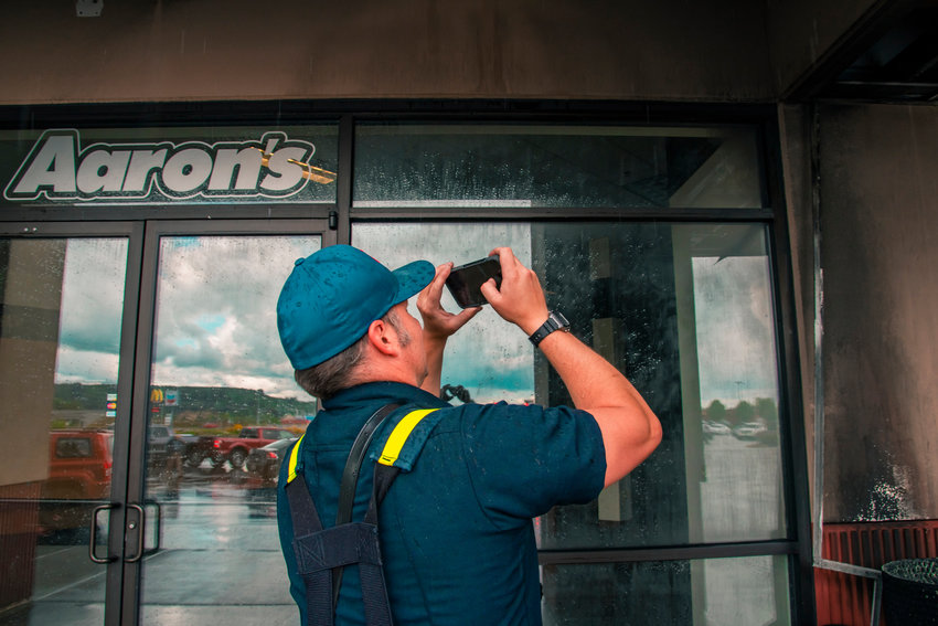A Chehalis firefighter takes photos of damage to the Twin City Town Center shopping plaza after alarms in multiple stores rang for a fire that started in a trash bin and triggered outside sprinkler systems on Wednesday.