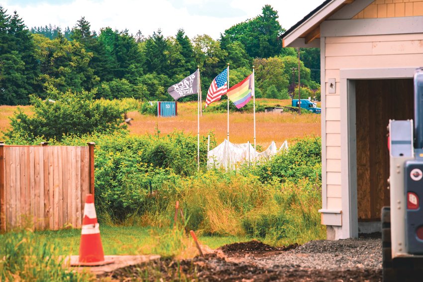 Flags on the Lewis County Lollipop Guild&rsquo;s property wave between homes on Monday. In a lawsuit, Lollipop Guild founder Kyle Wheeler alleges that local governments have favored Scott Marvin&rsquo;s Marvin Construction, LLC, which has &ldquo;repeatedly encroached&rdquo; and &ldquo;continually trespassed&rdquo; on his single-acre property.