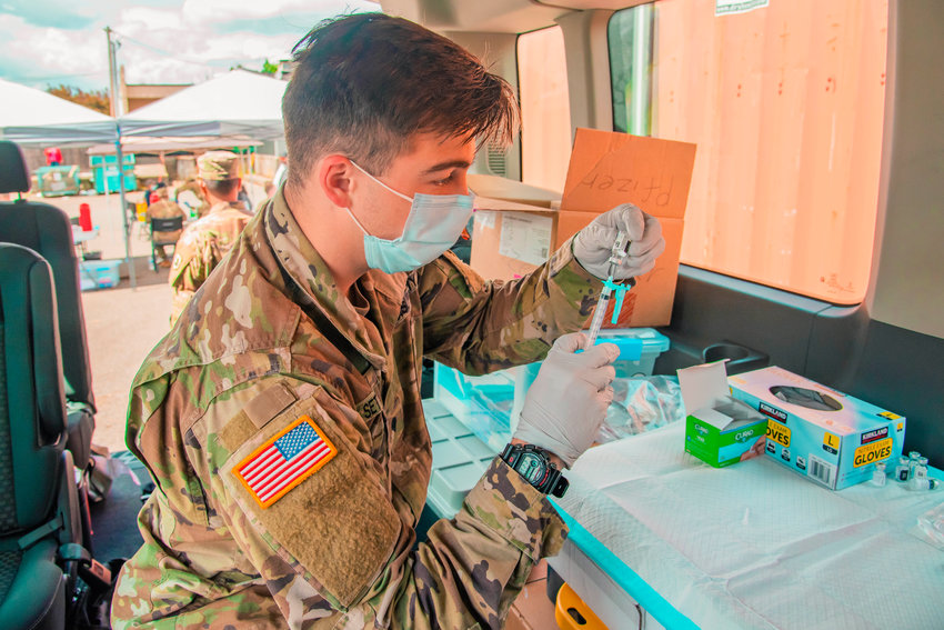 U.S. Army Specialist Settlecowski with the National Guard draws a dosage of the Johnson &amp; Johnson coronavirus vaccine from a vial during a clinic held at the Market Street Ace in Chehalis.