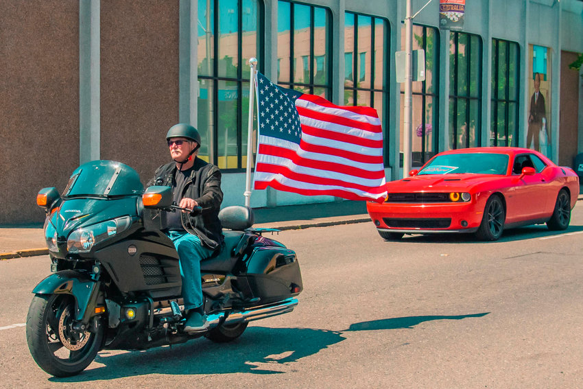 A rider displays an American flag on his motorcycle as he rides through downtown Centralia during a &ldquo;Patriotic Drive&rdquo; part of Summerfest in Centralia for Fourth of July, Sunday afternoon.