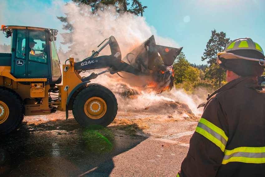 A firefighter watches as crews work to clear the roadway following a hay truck fire which ended on the southbound milepost 71 off-ramp for Interstate 5 on Thursday. Lewis County Fire District 5 responded. The off-ramp was closed for several hours as firefighters extinguished the fire.
