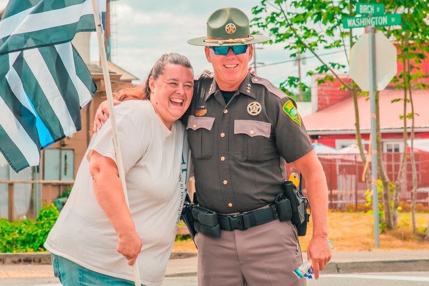 Dawn Miles smiles as she is stopped by Lewis County Sheriff Rob Snaza for a hug while carrying a &ldquo;Thin Blue Line&rdquo; flag on Saturday during the Napavine Funtime Festival parade.