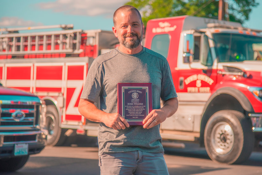 Jared Wenzelburger / jared@chronline.com  Josh Weinke poses for a photo with a Citizen&rsquo;s Hero Award he was honored with Thursday for rescuing a neighbor from a house fire in rural Chehalis last month.