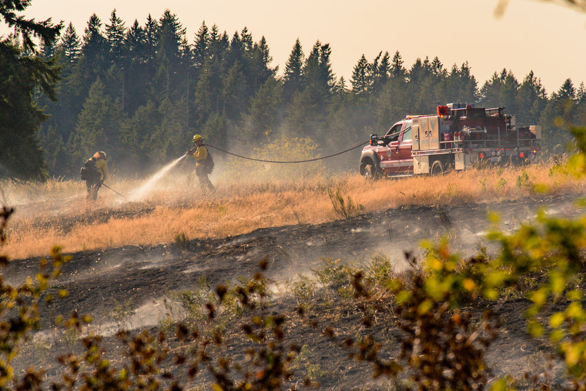 Department of Natural Resources fire crews work to put out a brush fire in the Scatter Creek area near Case Road in Maytown on Monday.