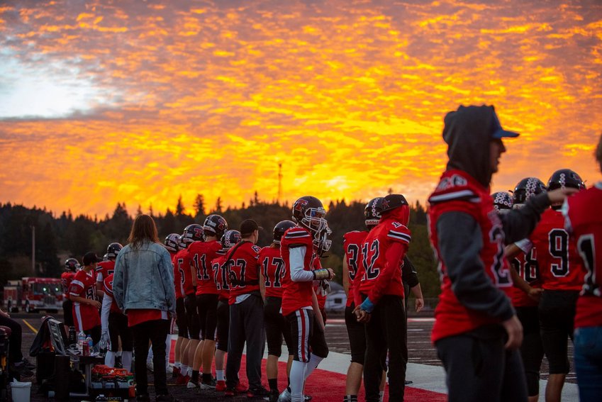 The sky turns gold as the Tenino High School football team looks on from the sidelines Friday evening in Tenino.
