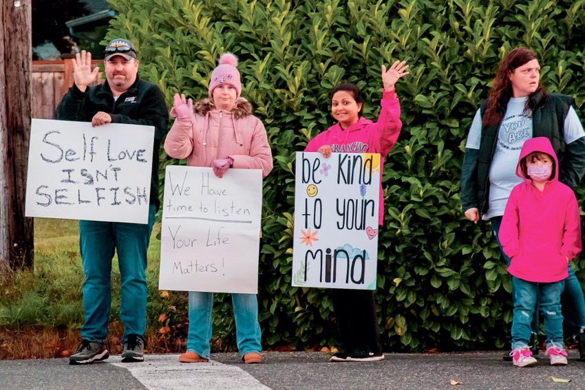Parents hold signs with supportive messages outside W.F. West High School Monday morning in Chehalis.