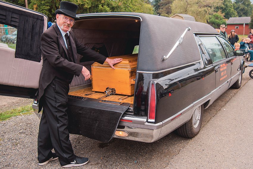 Steve Purcell smiles as he opens the back of &ldquo;Hearsela,&rdquo; a Cadillac hearse, to reveal a casket before the Casket Races outside Boo-Coda Town Hall in October 2021.