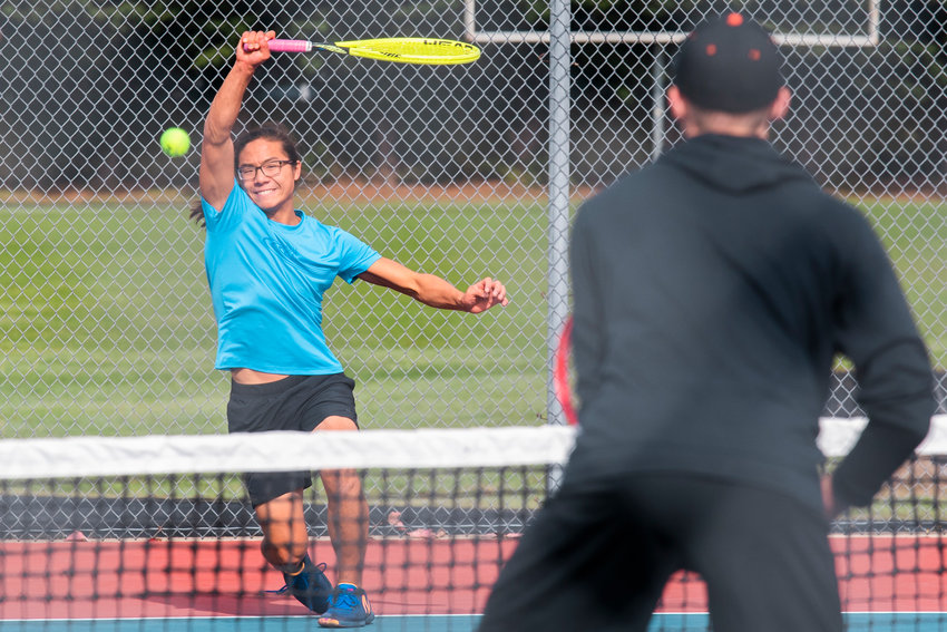 W.F. West&rsquo;s Joseph Chung smiles as he returns a shot during a doubles match at Black Hills High School Tuesday afternoon.