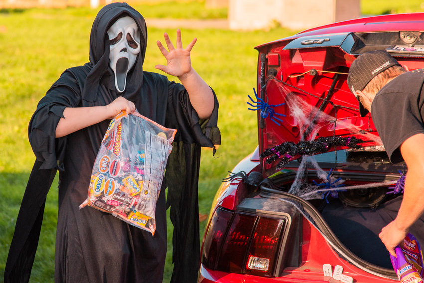 Ghostface waves while holding a bag of candy during Winlock's Trunk-or-Treat event on Halloween in 2021.
