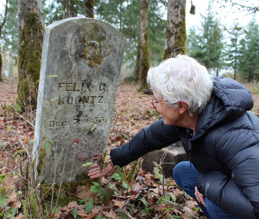 Lorie Spogen looks at the details on Felix Koontz's gravestone on her rural Chehalis property. While it was known the grave was on the property, its location had become overgrown and lost when the Spogens purchased the property this year