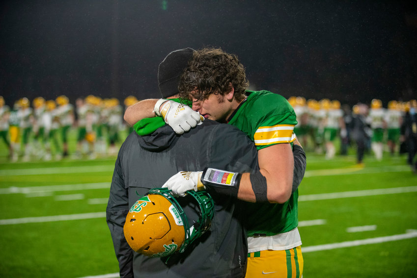 Tumwater senior Ryan Otton hugs a Thunderbirds&rsquo; assistant coach after the T-Birds lost 21-7 to Lynden in the 2A state football championship on Dec. 4 in Puyallup.