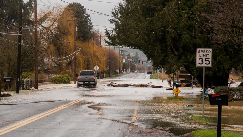 A truck drives by debris in the Skookumchuck River last January in Centralia as floodwaters flow over North Pearl Street.