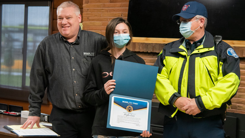 Haylee Laur, 15, holds up the Maglite Tough Award Thursday morning inside the Virgil R. Lee Community Building in Chehalis while being recognized for saving her two siblings and the family pug from a house fire in Winlock last month.