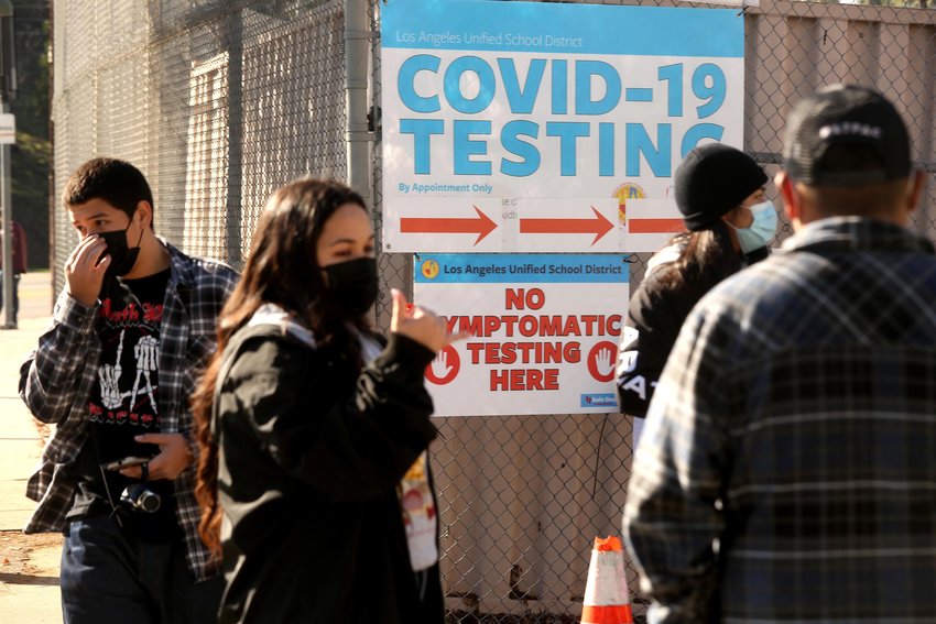 A support worker, second from left, directs Los Angeles Unified School District students and staff who wait in line for a COVID-19 test at a walk-up site at the El Sereno Middle School in the El Sereno neighborhood of Los Angeles on Jan. 4, 2022. (Genaro Molina/Los Angeles Times/TNS)