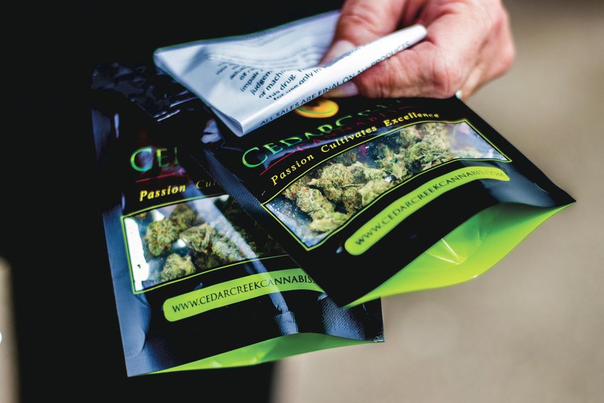 FILE PHOTO &mdash; A customer holds up their purchase of marijuana outside a Grand Mound dispensary.