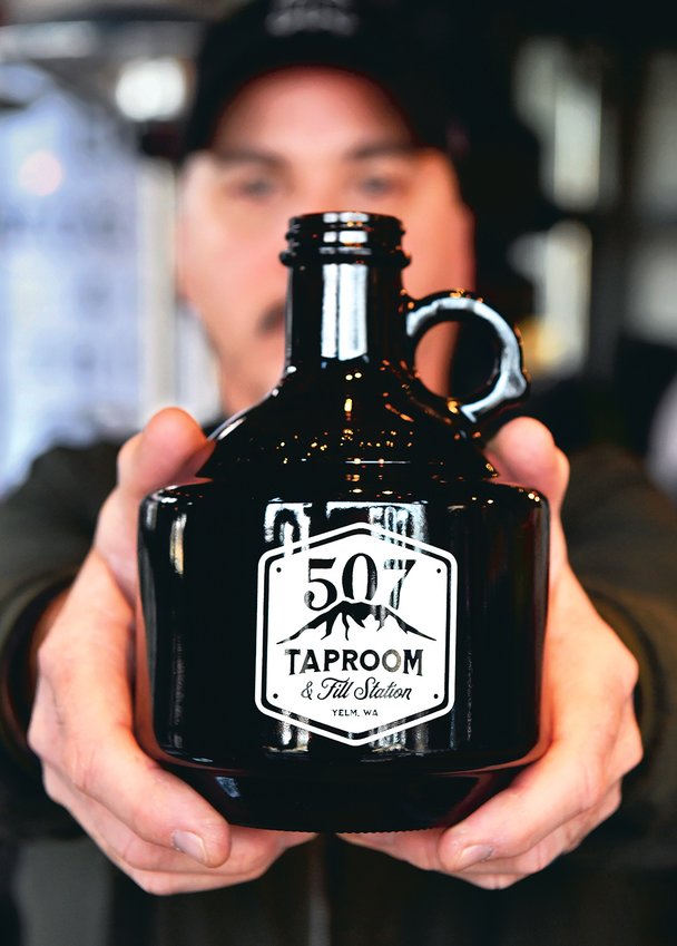 Bill DeVore, who owns 507 Taproom and Filling Station in Yelm, displays a 32-ounce &quot;growler&quot; to-go bottle at the business in this file photo.