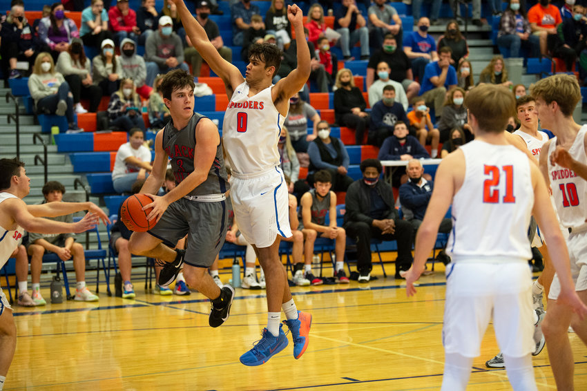 Johnnie Stallings of Black Hills (left) looks to make a pass as Ridgefield&rsquo;s Sid Bryant (0) defends during Ridgefield&rsquo;s 54-40 win over the Wolves in the first round of the 2A district boys basketball tournament at Ridgefield.