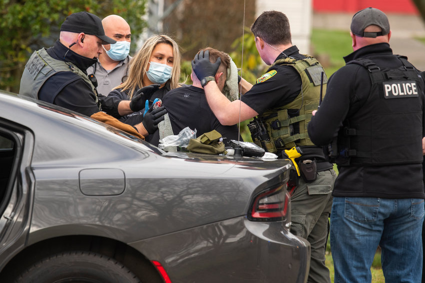 A member of law enforcement is treated for injuries and helped into the back of an ambulance in the 100 block of Southwest Alfred Street in Chehalis after responding to a call.