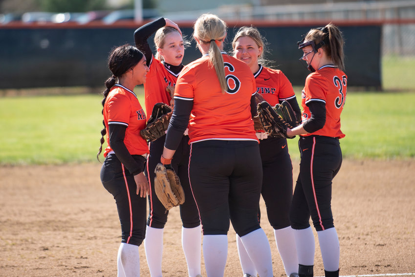 Napavine softball players meet on the mound during a home game against Ilwaco on Saturday, March 12.