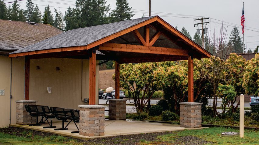 A man walks away with an umbrella in hand after stopping under a newly constructed pergola outside the Tenino Timberland Library to get out of the rain on Monday. In 2021, the city received a $26,414 grant to pave the city-owned parking lot behind the Sandstone Caf&eacute;, but because of the increasing costs of construction and product delays, the district switched the grant to build a visitor and community outdoor covered space next to the Tenino Timberland Library for those who visit the Tenino Farmers Market and visitors on the Yelm-Rainier-Tenino Trail to do things like read and eat lunch in.