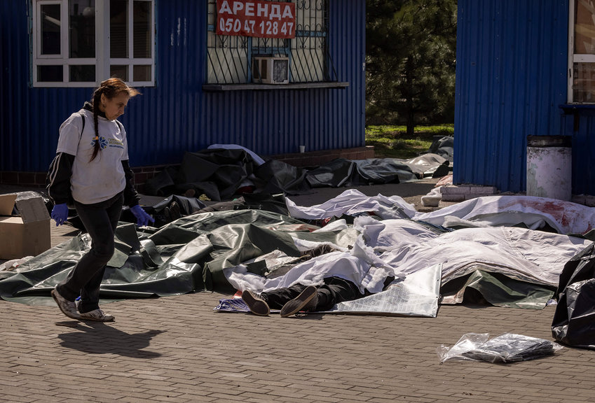 A woman passes by bodies covered with plastic sheets after a rocket attack killed at least 35 people on April 8, 2022 at a train station in Kramatorsk, eastern Ukraine, that was being used for civilian evacuations. (Fadel Senna/AFP via Getty Images/TNS)