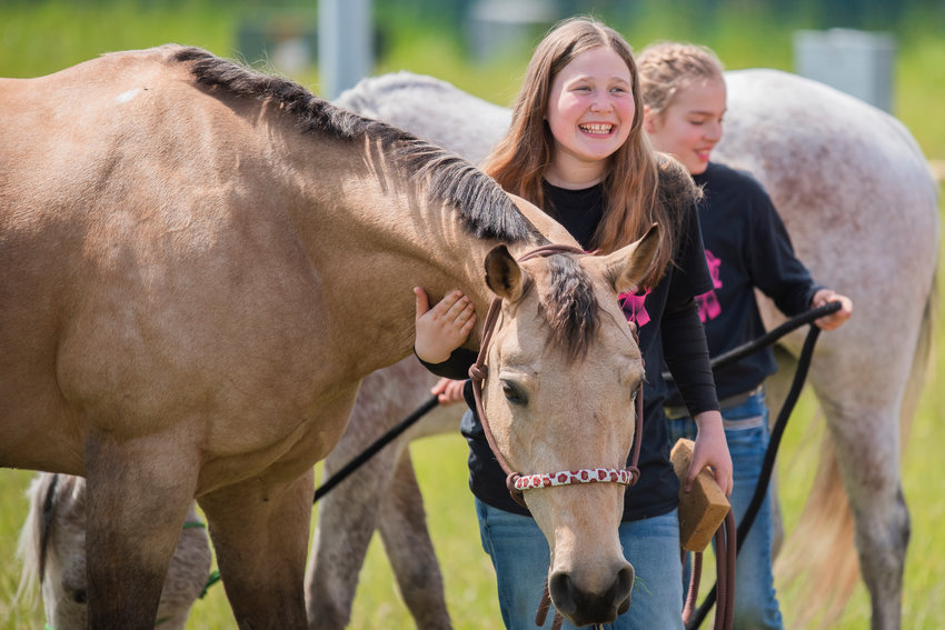 Rikki Workman smiles as she pets and cleans her horse, Butter, at the Southwest Washington Fairgrounds alongside Bristol Osborn and her horse Annie while describing the arena as a &ldquo;swamp&rdquo; on Sunday. Friday marked the return of the Spring Youth Fair, which was canceled the two previous years due to COVID-19. The Spring Youth Fair is essentially a smaller version of the Southwest Washington Fair that focuses on children. Look for information on next year&rsquo;s run online at springyouthfair.org.