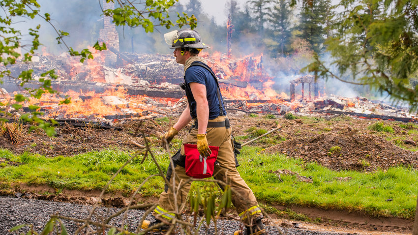 Zach Brotherson, with Lewis County Fire District 6, walks in front of a house following a live fire practice burn at 2517 Jackson Highway in Chehalis.
