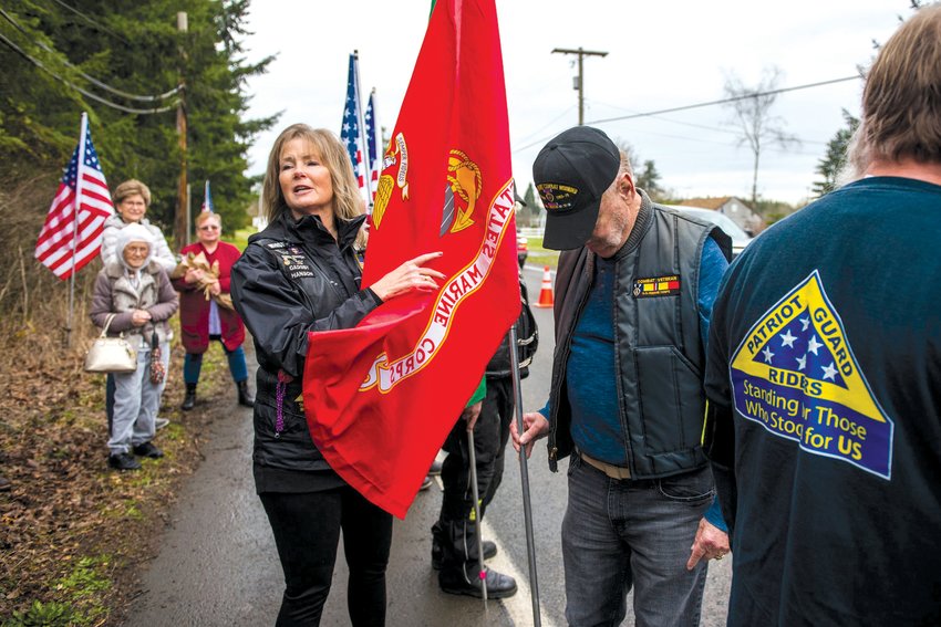 Marine Corps veteran Roger Flinn, right, lowers his head as Mary Astrid, center left, talks about his service before the unveiling of a &quot;Purple Heart County&quot; sign in the 3900 block of Harrison Avenue in 2020.