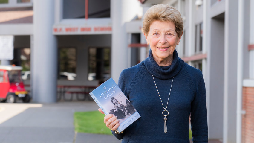 Barbara Sommer Feigin smiles for a photo with her book &ldquo;My American Dream&rdquo; while standing outside W.F. West High School  in Chehalis.