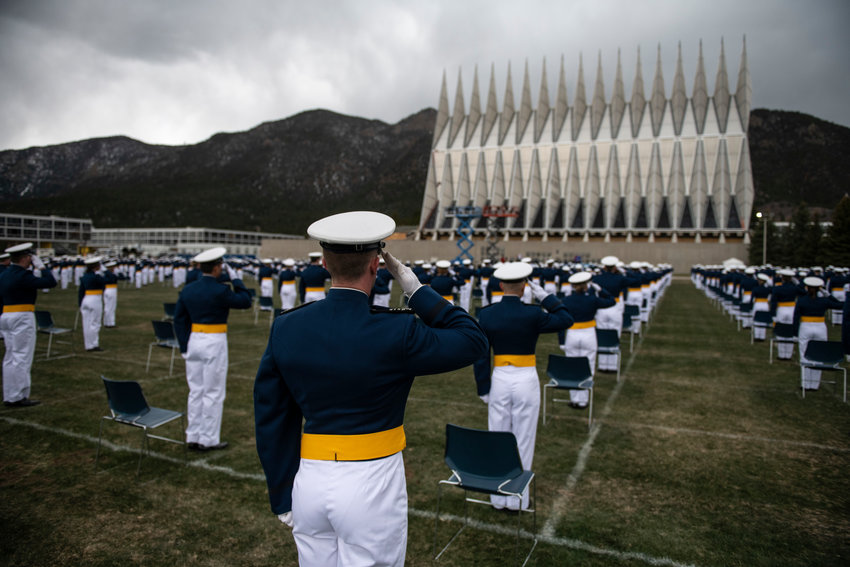 Air Force Academy cadets, spaced eight feet apart, salute as the national anthem plays at the start of their graduation ceremony on April 18, 2020 in Colorado Springs, Colorado. Four cadets may not be eligible to graduate with the class of 2022 because they did not get vaccinated in accordance with military academy policy. (Michael Ciaglo/Getty Images/TNS)