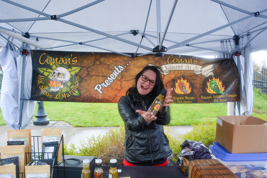 Fawn Hogue presents Conan&rsquo;s roasted habanero mango hot sauce at the Conan&rsquo;s Hot Sauces and Marinades booth at the Battle Ground Farmers Market in the parking lot of the community center on May 12.