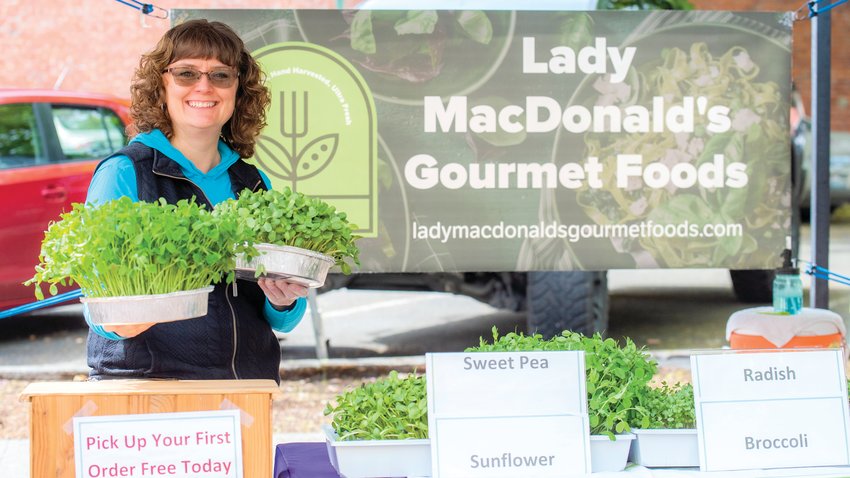 Heidi MacDonald, with Lady MacDonald&rsquo;s Gourmet Foods, smiles while holding up microgreens at Pine Street Plaza during her Centralia Farmers Market debut Friday morning.