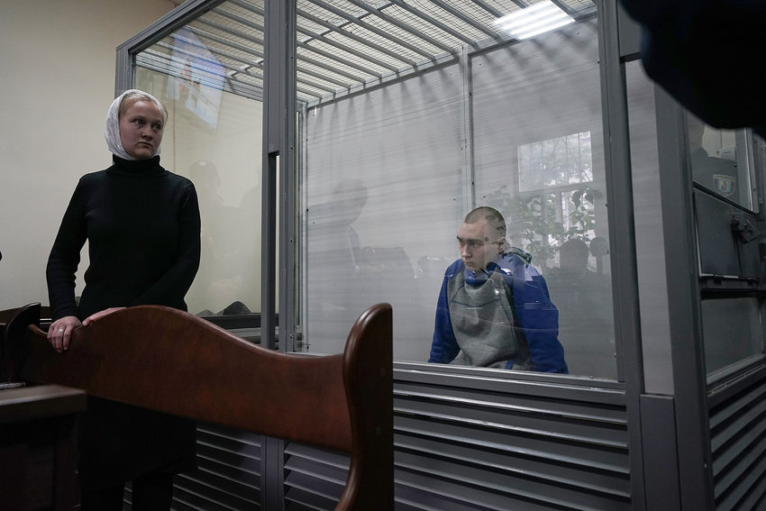 A translator speaks to court officials as captured Russian soldier, Sgt. Vadim Shishimarin, 21, sits in a defendants cage during a court hearing on May 18, 2022, in Kyiv, Ukraine. Sgt. Shishimarin pleaded guilty to shooting a civilian on a bicycle in the village of Chupakhivka, Sumy Region, days after Russia's invasion of Ukraine on Feb. 24. The trial of the Russian soldier was the first that Ukraine has conducted since the invasion related to charges that could be considered war crimes. (Christopher Furlong/Getty Images/TNS)