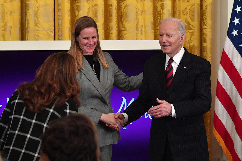 U.S. President Joe Biden, right, greets Cindy Parlow Cone, president of the US Soccer Federation, as he arrives for the Equal Pay Day event to celebrate Womens History Month in the East Room of the White House in Washington, D.C., March 15, 2022. (Nicholas Kamm/AFP/Getty Images/TNS)