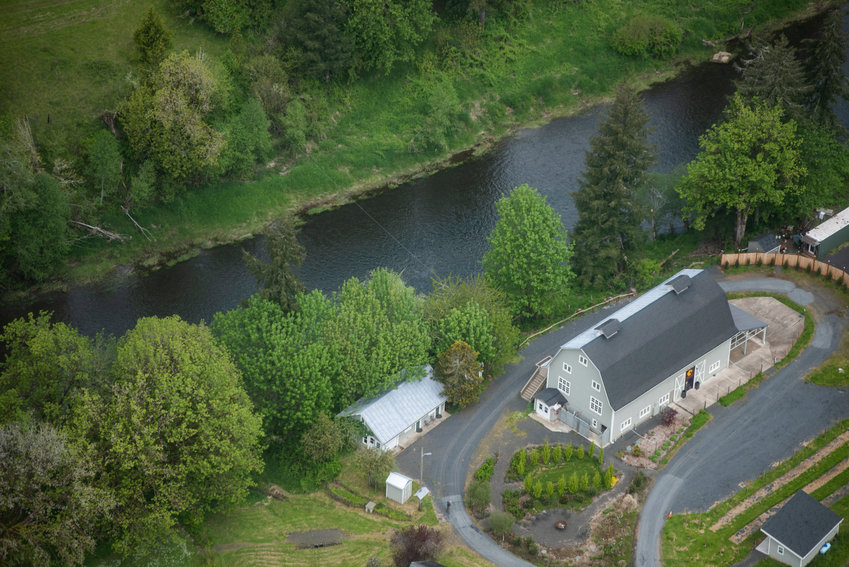 The Owl and Olive, a restaurant with Mediterranean and Italian inspired food between Doty and Pe Ell, is pictured beside the Chehalis River from above. A cable from the USGS Doty Chehalis River gage can be seen stretching across the water in the center of the photo.