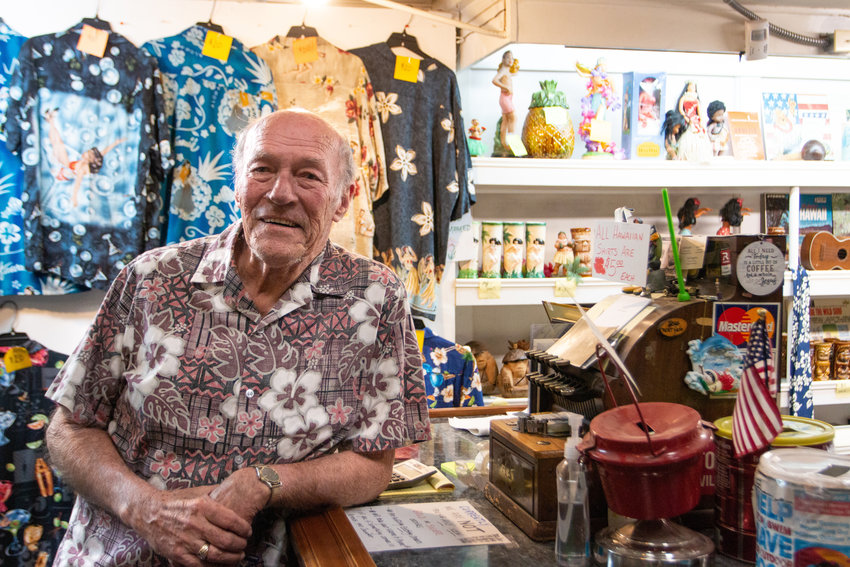 Pat Slusher, owner of Pat Slusher&rsquo;s Coin Shop, poses with his antique register and wall full of Hawaiian items. At the age of 79, he plans to retire to his oceanside property and relax with his wife Phoebe.