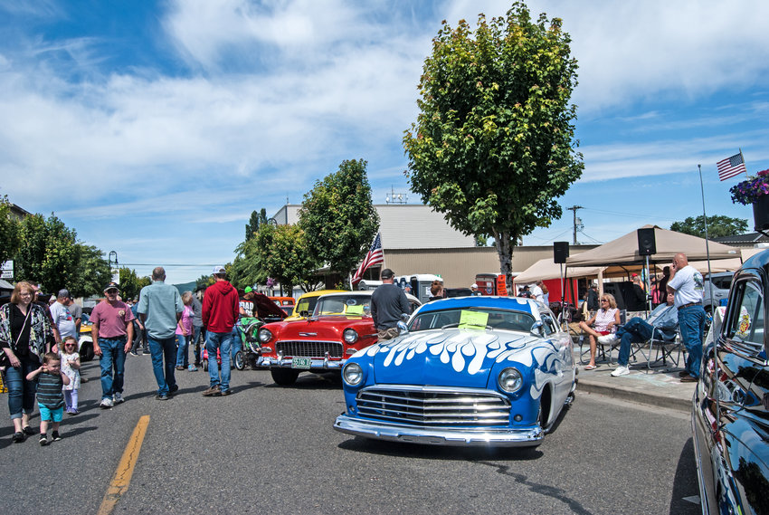 A number of classic cars are on display at a cruise-in during the 2019 Planters Days festival in Woodland as a crowd looks on.