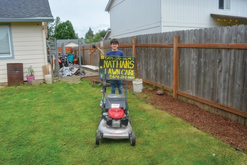 Nathan Pascu is pictured with his lawnmower and weed whacker at his grandmother&rsquo;s house with his Nathan&rsquo;s Lawn Care sign on June 1.