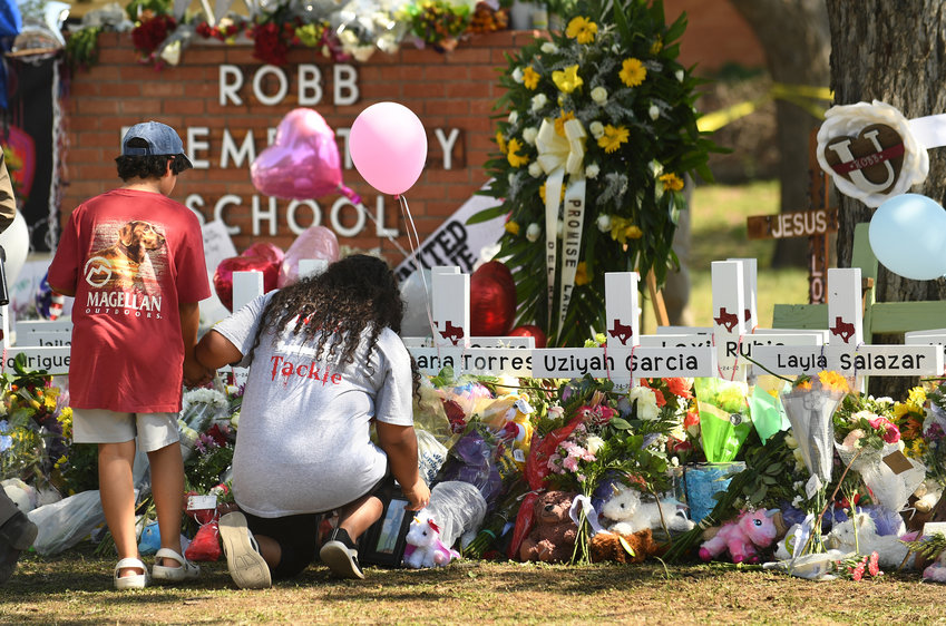 Family members place a picture at a memorial outside Robb Elementary School in Uvalde, Texas, where 19 students and two teachers died when a gunman opened fire in a classroom. (Wally Skalij/Los Angeles Times/TNS)