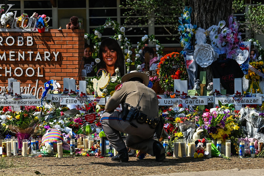 A police officer clears the makeshift memorial before the visit of US President Joe Biden at Robb Elementary School in Uvalde, Texas, on May 29, 2022. (Chandan Khanna/AFP/Getty Images/TNS)