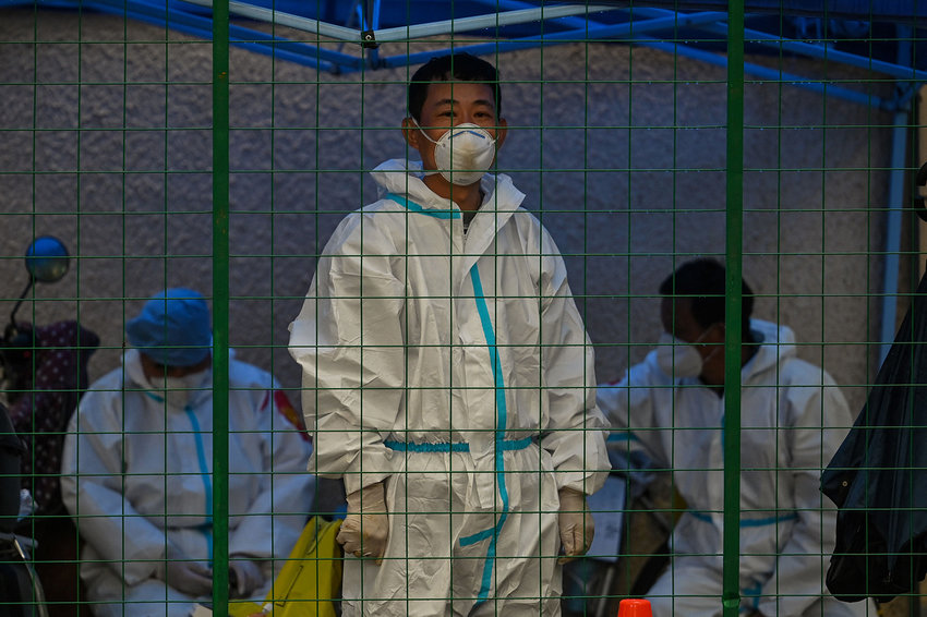 A worker wearing personal protective equipment (PPE) stands behind a fence in a residential area under Covid-19 lockdown in the Huangpu district of Shanghai on June 13, 2022. (Hector Retamal/AFP via Getty Images/TNS)